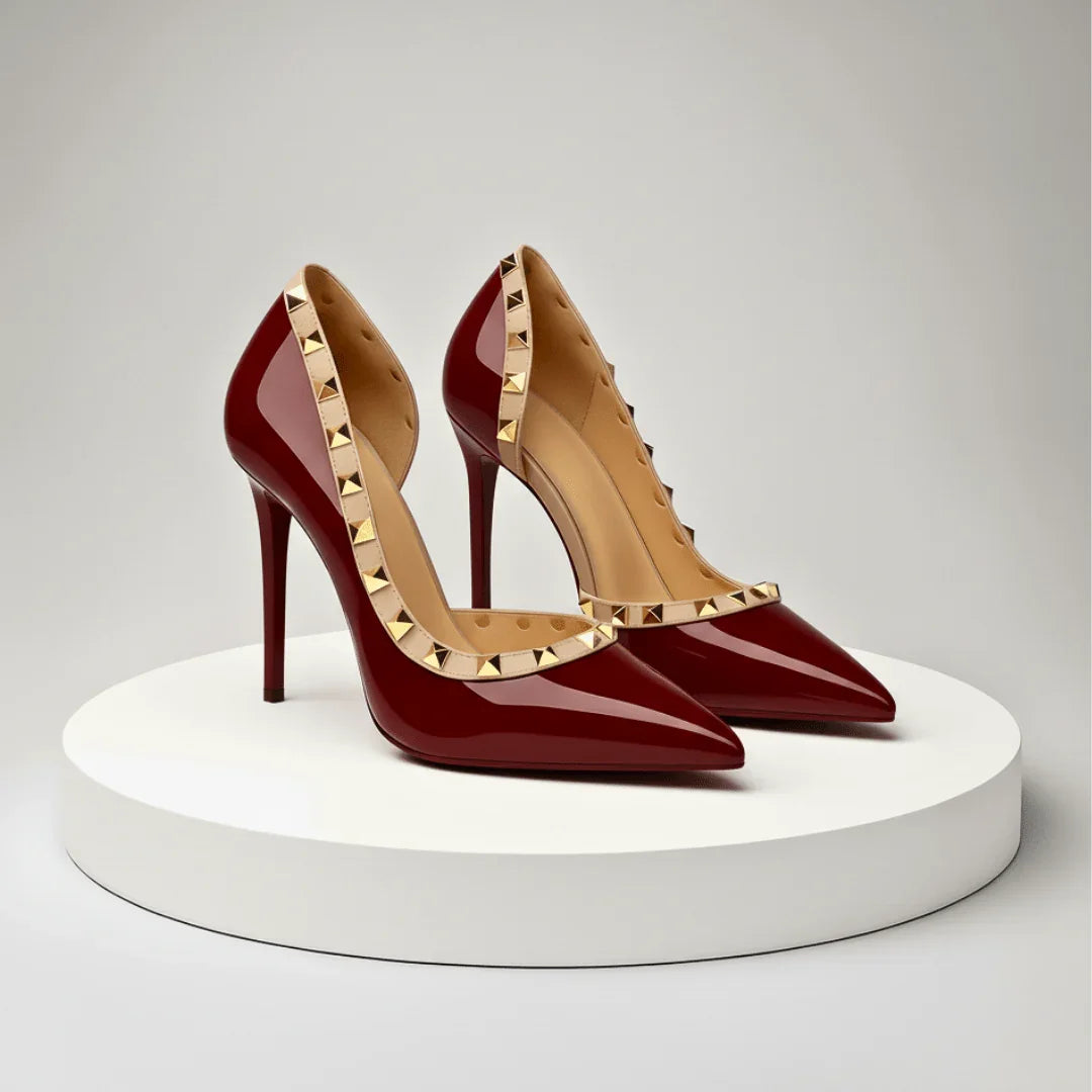 Pair of red high-heeled shoes with gold studded details on a white platform.